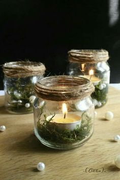 three mason jars filled with moss and lit candles