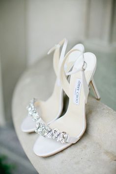 a pair of white high heeled shoes sitting on top of a table