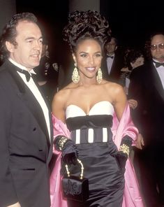 a man in a tuxedo standing next to a woman in a black and white dress