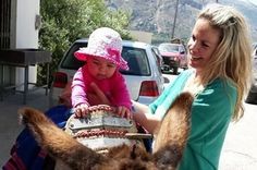 a woman and child petting a donkey on the back of it's head