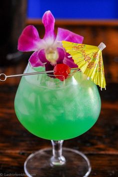 a green cocktail garnished with an orchid