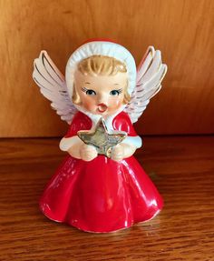 an angel figurine holding a star on a wooden table