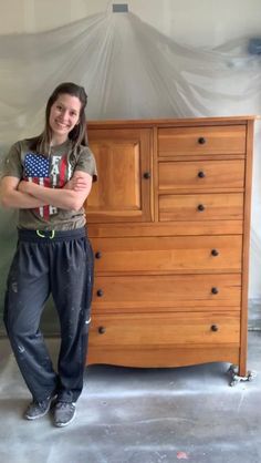 a woman standing next to a wooden dresser