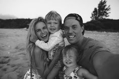 a man, woman and two children are posing for a photo together on the beach