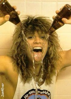 a woman with long hair holding two chocolate cups in front of her face and water pouring out of her mouth