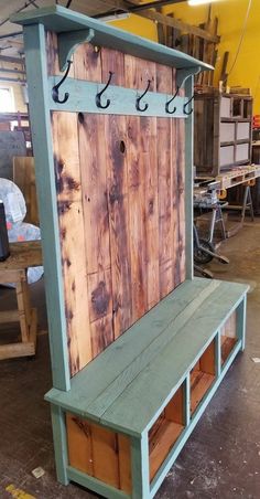 a bench made out of wooden boards with hooks on the back and shelves below it