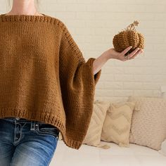 a woman is holding a knitted ball in one hand and an apple in the other