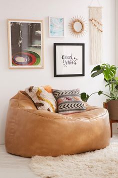 a living room filled with lots of furniture and pictures on the wall next to a plant