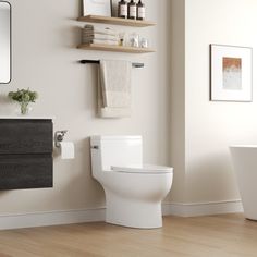 a white toilet sitting in a bathroom next to a bath tub and wooden flooring