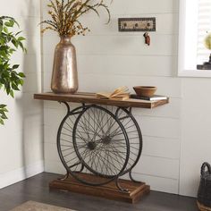 a table with a bike wheel on it in front of a potted plant and books