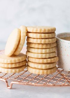 a stack of shortbread cookies next to a cup of coffee on a wire rack