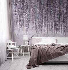 a bedroom with purple flowers on the wall and white bedding in front of it