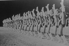 an old black and white photo of people holding up their hands