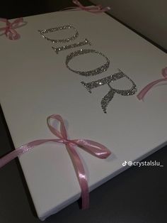 a white box with pink ribbon and glitter name on it