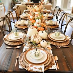 a dining room table set for thanksgiving with pumpkins and gourds on it