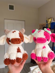 two small stuffed animals are being held up in front of the camera, one is brown and white