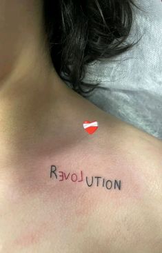 a woman with a small tattoo on her chest that says'revolution'in cursive writing