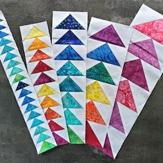 four different colored paper pieces are arranged in the shape of an upside down triangle on a gray surface