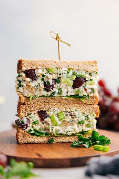 two sandwiches stacked on top of each other with cheese and vegetables in the middle, sitting on a cutting board