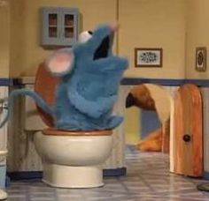 the sesame street character is sitting on the toilet in the bathroom with his head sticking out