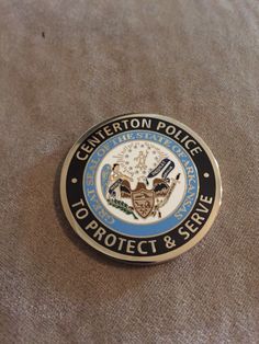 a close up of a police badge on a bed sheet with the words, centerton police department to protect & serve