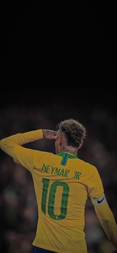 a soccer player saluting to the crowd with his hand on his head while standing in front of an audience