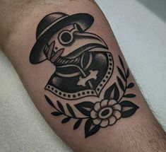 a man's arm with a black and white tattoo design on it, featuring a bird wearing a hat