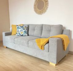 a gray couch with yellow throw pillows and a mirror above it in a living room