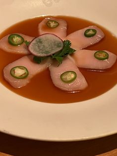 a white plate topped with meat and veggies covered in gravy on top of a wooden table