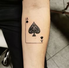 a man with a tattoo on his arm has a playing card in the shape of a spade