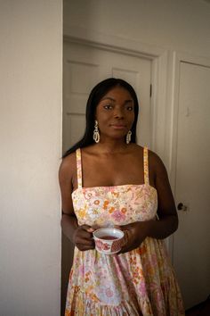 a woman standing in front of a door holding a paper plate and looking at the camera