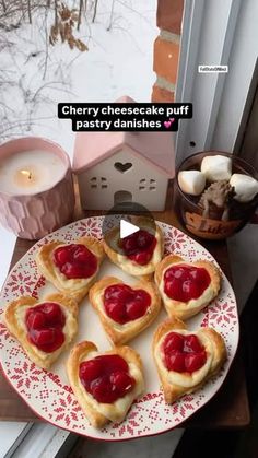 heart shaped pastries on a plate next to a candle and some other food items