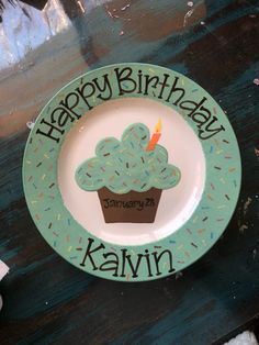 a happy birthday plate with a cupcake design on the front, and a candle in the middle