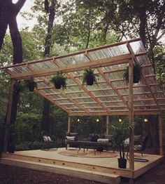 an outdoor patio with a pergolated roof and seating area surrounded by trees in the background