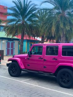 a bright pink jeep parked on the side of the road in front of palm trees