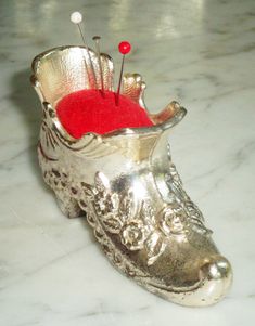 a silver shoe with a red button in it on a marble counter top next to a pair of scissors