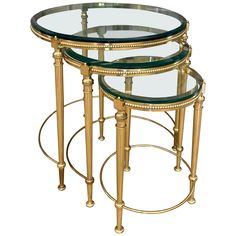 three round glass tables with gold trimmings and metal bases, all stacked on each other