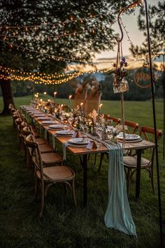 an outdoor dinner table set up with candles and place settings