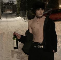 a shirtless man holding a bottle of wine in the middle of a snow covered street