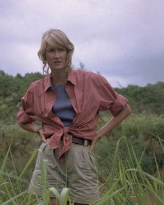 a woman standing in tall grass with her hands on her hips