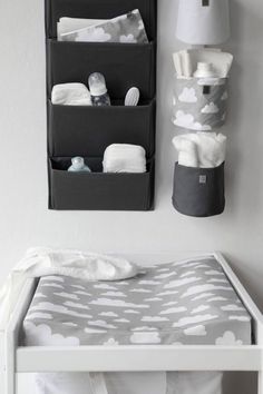 a baby crib with two storage bins hanging on the wall next to it