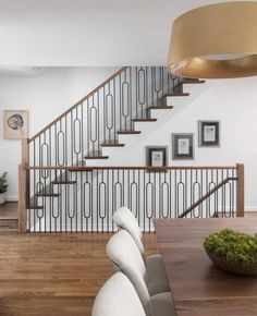 a dining room table and some chairs in front of a stair case with pictures on the wall