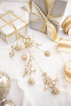 a white table topped with gold and silver decorations next to a gift box on top of a table