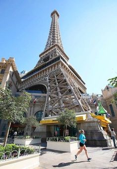 the eiffel tower is very tall and has many people walking around in front