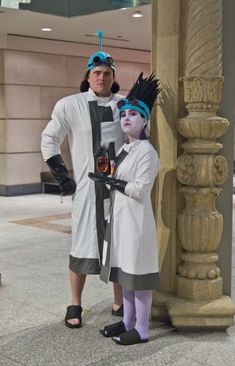 two people dressed in costumes standing next to each other near a pillar and pillars with statues on it