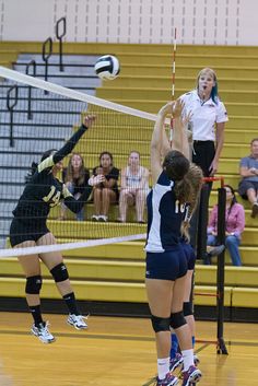 two girls playing volleyball in front of an audience