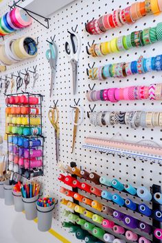 a peg board with many different colored spools and scissors hanging on the wall