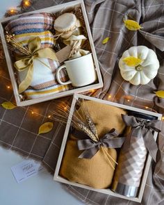 two boxes filled with gifts on top of a blanket next to pumpkins and candles