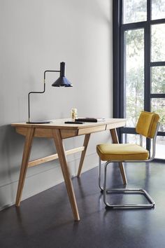 a desk with a chair next to it and a lamp on the table in front of it