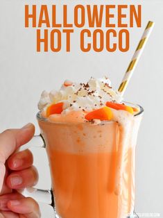 a hand holding a glass with candy corn hot chocolate in it